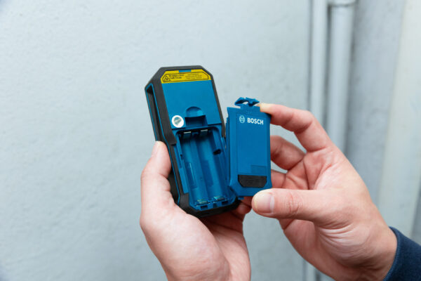 The open battery compartment of a Bosch GLM 50-27 CG laser measure.