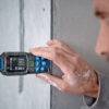 Close-up of a Bosch 50m laser measure taking a horizontal distance reading on a concrete wall.